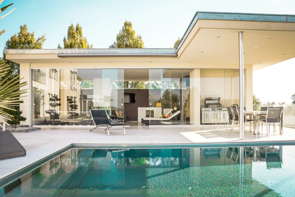 Maison contemporaine de plain-pied avec de larges façades vitrées, une terrasse couverte et une piscine.